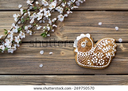 Easter chicken glazed cookie on wooden background with cherry blossom