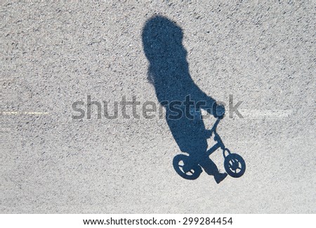 Shadow of a toddler riding a balance bike.