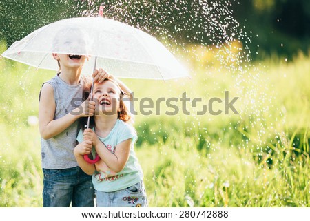 happy kids playing outdoor in raining spring park. shallow depth of field,focus on children or raindrops