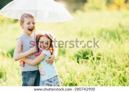 Happy children in the rain, shallow depth of field,  Funny kids playing outdoors in spring park. Brother and sister playing in the rain in summer, focus on children or raindrops