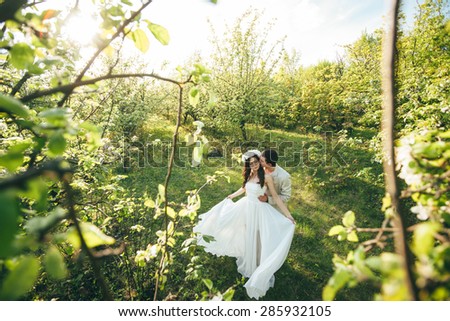 couple in love outdoors in a green garden, the bride and groom walk and having fun. The girl in a white dress with a wreath on his head walks with a guy