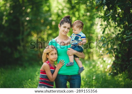 Happy mother and children enjoy life, happy family walking in the garden, Mom hugging children