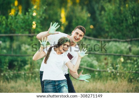 beautiful young couple playing with colorful paints outdoors. Couple throwing each other colorful paint. Man and woman spend fun time outdoors