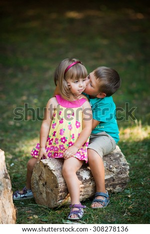 boy and girl playing on the meadow in the park. Brother sister kisses