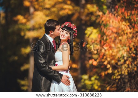 young woman and man embracing against the backdrop of autumn forest. A couple in love in beautiful dresses embracing fall. Warm autumn portrait of men and women
