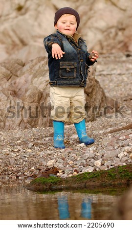 liitle boy throwing stones in a rock pool on a beach