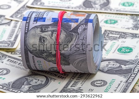 Hundred new dollar roll  up with red rubber  on dollars background