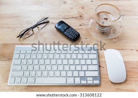 computer keyboard phone glasses and cup of coffee on wooden office table, top view