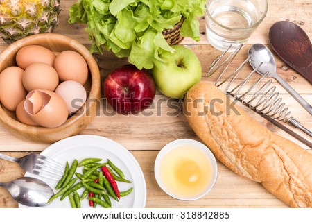 eggs vegetable bread chilli pineapple spoon fork whisk chopsticks  green and red apple on wooden table