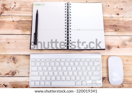 pen on the notebook with keyboard mouse old wooden background