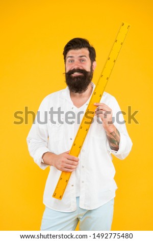 Man bearded hipster holding ruler. Measure length. Size tall and length. Big size. Measure. Geometry theorem. Actual size. School teacher. Small little big large. Does size really matter. One meter. 商業照片 © 