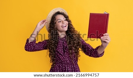 cheerful child with frizz hair recite book on yellow background Imagine de stoc © 