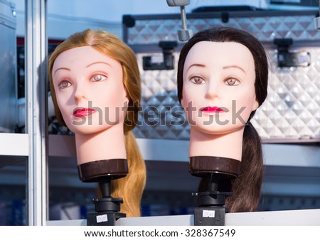 Two female simulating human faces mannequins for makeup with blonde and brunette hair styles indoor, horizontal picture