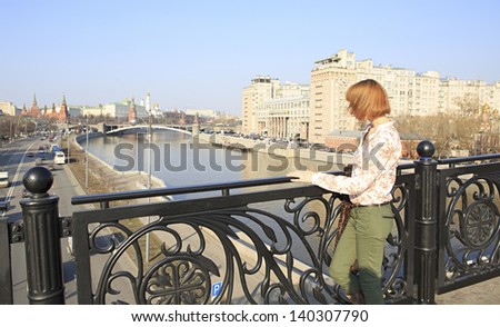 Beautiful girl walking around Moscow (stopped on the bridge).