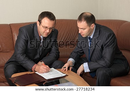 Signing of agreement two businessmen is in an office.