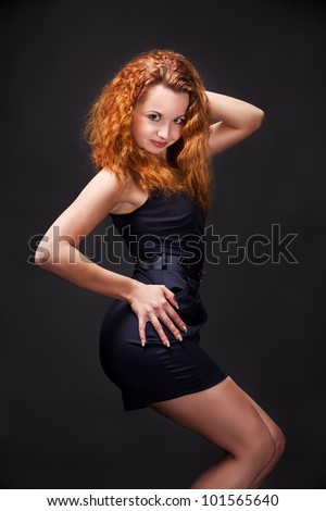 Redhead young girl in dark blue dress posing in studio