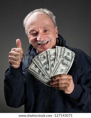 Happy elderly man showing fan of money and sign OK with fingers
