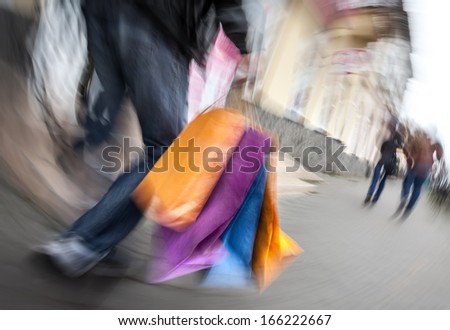 Holiday sales. Man with many shopping bags in his hand. Intentional motion blur