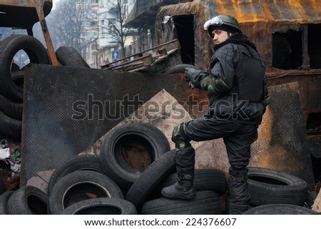 KIEV, UKRAINE - Feb 12, 2014: Mass anti-government protests in the center of Kiev. Barricades, ruin and chaos on Hrushevskoho St. Self-defense fighter on the barricades