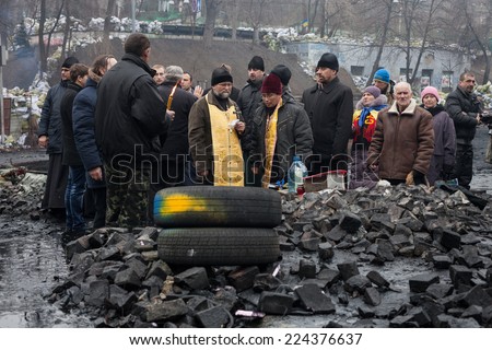 KIEV, UKRAINE - Feb 12, 2014: Mass anti-government protests in the center of Kiev. Barricades, ruin and chaos on Hrushevskoho St. Prayer at the place of death of self-defense fighter