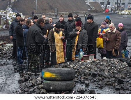 KIEV, UKRAINE - Feb 12, 2014: Mass anti-government protests in the center of Kiev. Barricades, ruin and chaos on Hrushevskoho St. Prayer at the place of death of self-defense fighter