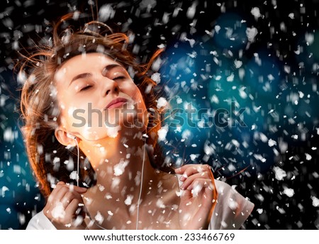 Beautiful woman listening to music during a snowfall