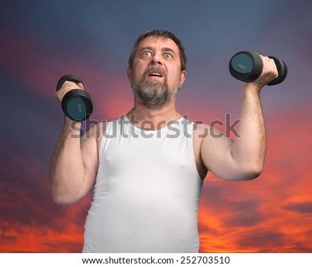 Morning exercises. Elderly man exercising with dumbbells against the morning sky