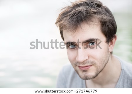Soft focus portrait of a young man with blue eyes on a light blurred natural background
