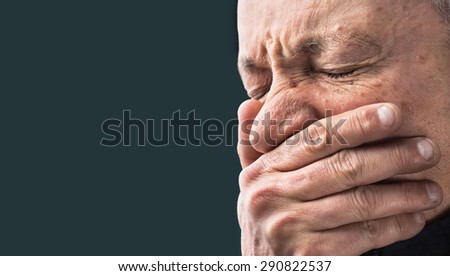 Toothache. Portrait of an elderly man with face closed by hand on dark background with copy-space