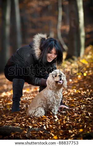 Girl and cocker spaniel in the autumn forest. Focus mainly on the dog