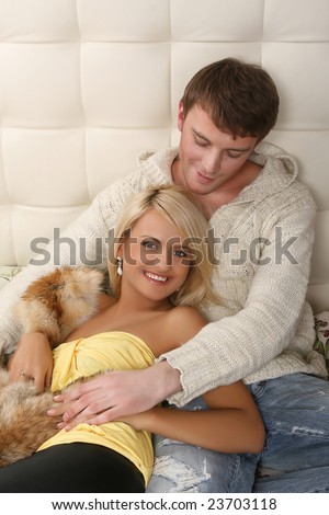 romantic young man and woman sitting on bed and hugging