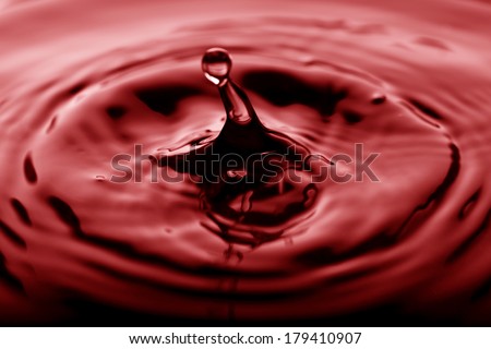 Water drop falling into red water