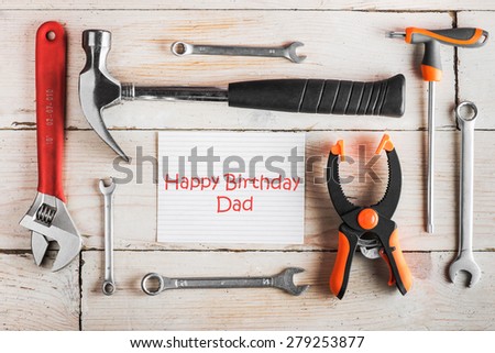 Greeting Card to Happy Birthday Dad, concept, set of different tools: a hammer, wrench, screwdriver, various spanners, clamp and tablet with text \