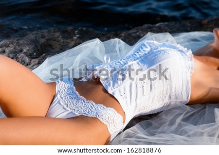 woman lying on a rock in a corset