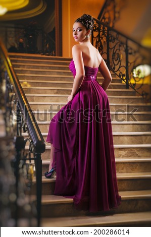 young woman in a long dress lying on the stairs in the hotel lobby