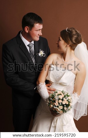 Loving newlyweds standing on a brown background