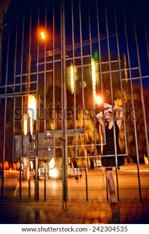 Emotions. Pretty woman posing in cage outdoors at night