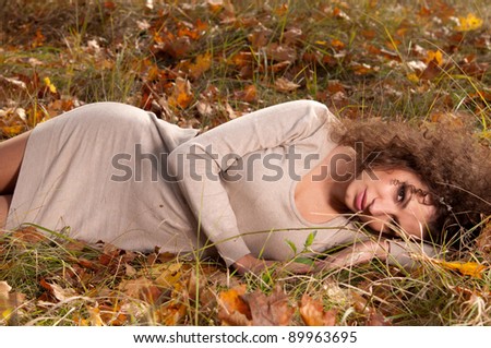 woman in elegant clothes lying on the leaves