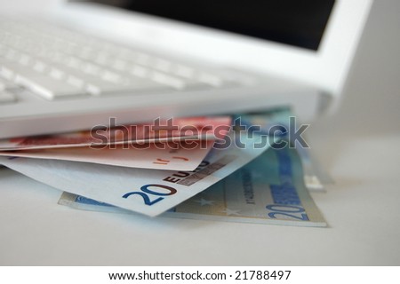 Euro bills and the computer (on-line shopping or online banking concept)