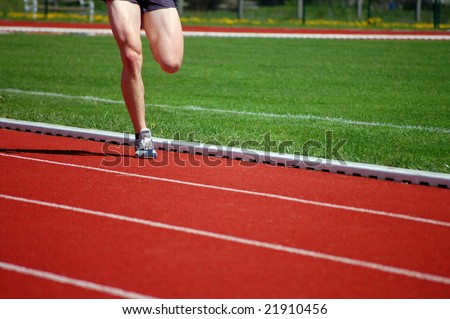 Athlete in shorts and running shoes warming up on the running track
