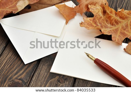 Fountain pen on empty letter with autumn leaves on a wooden table