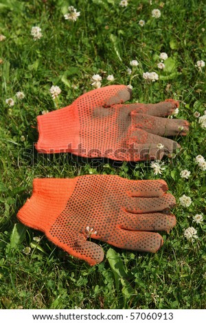 Old and dirty garden gloves on grass background.