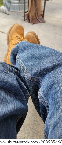 Mans legs I'm blue jeans and boots legs crossed relaxing Stock fotó © 
