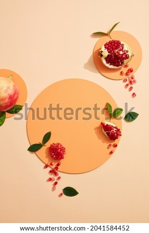 Empty background for cosmetics with pomegranate extract. Whole pomegranate and pomegranate seeds on podium circle on color background. Top view. Flat lay image. 