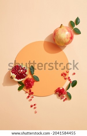 Top view cosmetic background for product presentation with pomegranate extract. Empty Cosmetic circle podium and pomegranate extract on light orange background. Flat lay