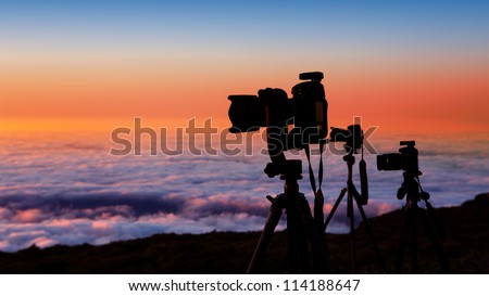 camera tripods of nature photographer work in high mountain sunset over sea of clouds