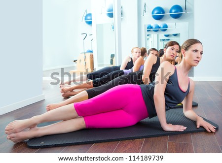 Pilates women group lying on mat with gym instructor on the front