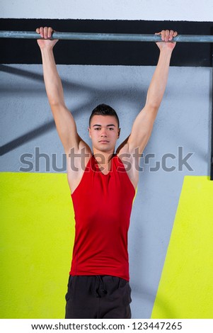 Fitness toes to bar young man pull-ups 2 bars workout exercise at gym