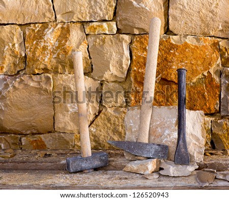 Hammer mason tools of stonecutter masonry work in a construction stone wall
