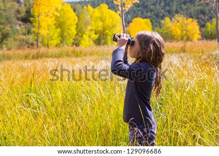 Explorer binocular looking kid girl in yellow autumn nature outdoor